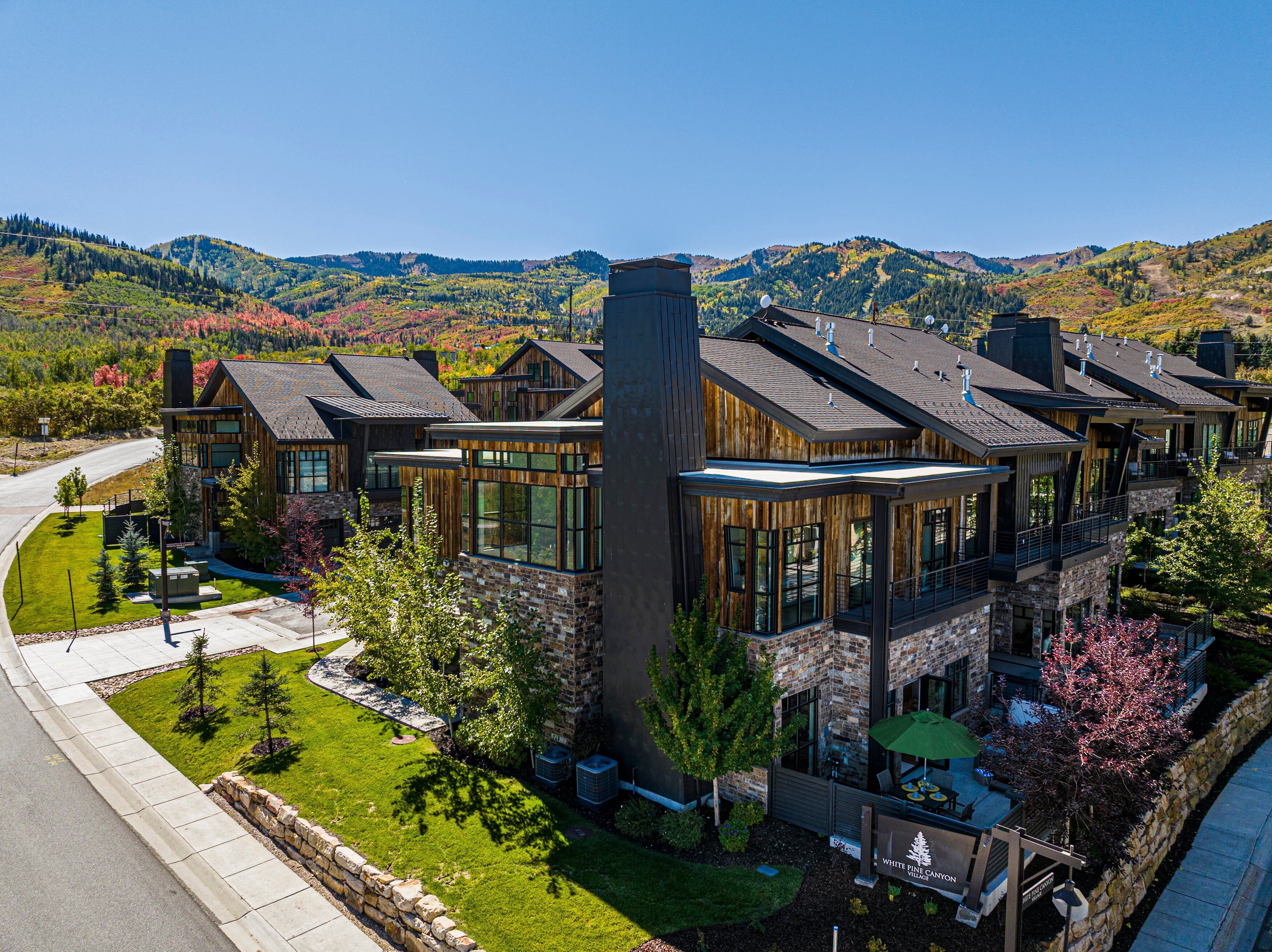 A modern multi-story building with large windows, a stone facade, and a view of a mountainous landscape.