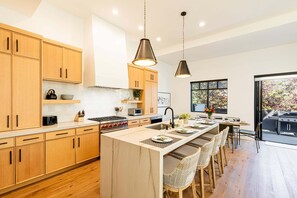 A modern kitchen with wooden cabinets, a central island, pendant lighting, and a view of the outdoors. - Luxury townhome in the Canyons Village Private hot tub (Park City)