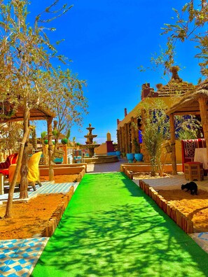 A courtyard with a central green pathway, surrounded by trees and traditional architecture.