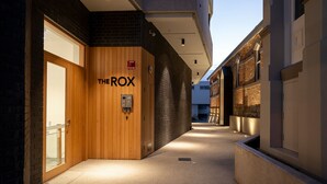 A corridor with a wooden door labeled "THE ROX" and a fire alarm. - The Rox Hobart (Hobart)