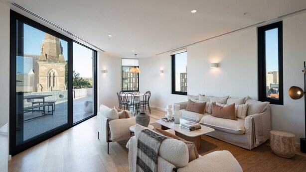 A spacious living area with a large window, a dining area, and a sofa set. - The Rox Hobart (Hobart)