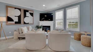 A modern living room with a fireplace, a sofa set, and artwork on the wall. - Convenient and Accessible, Park + BBQ + Pool +Gym by Hello Hideout (San Jose)