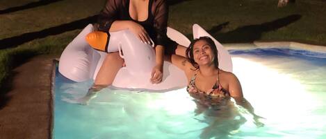 A swimming pool with two people on inflatable floats.