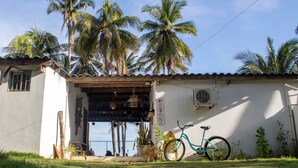 Una casa con porche, bicicleta y palmeras.