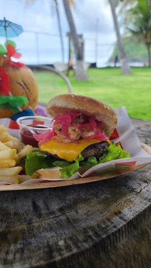 Savor a classic burger with a grilled patty, melted cheese, and pickled vegetables, served with French fries and ketchup.