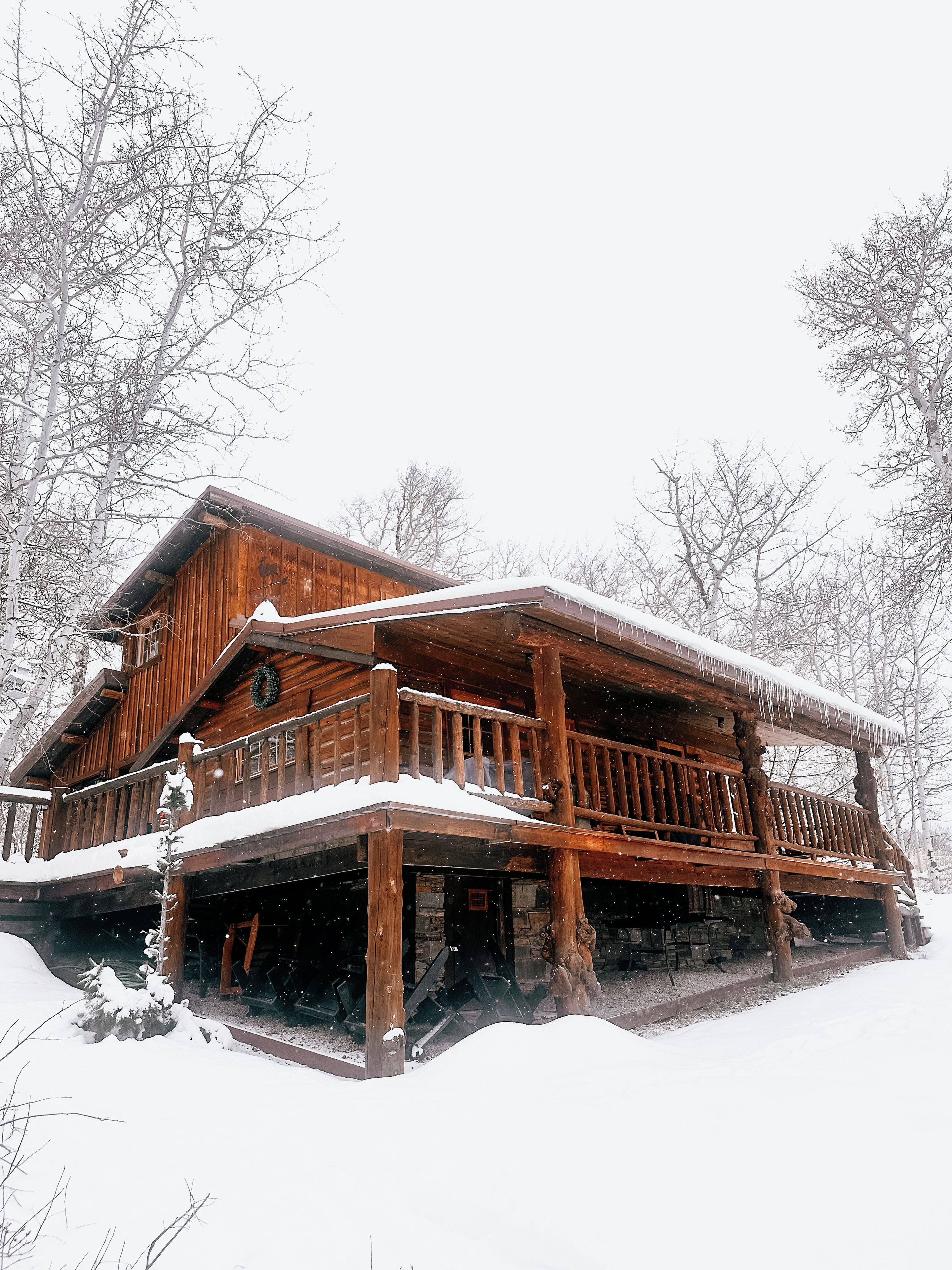 A wooden cabin with a snow-covered balcony and a porch.