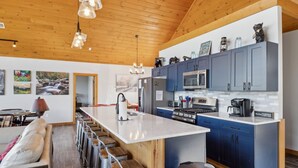 A modern kitchen with blue cabinets, a stainless steel refrigerator, a microwave, and a coffee maker.