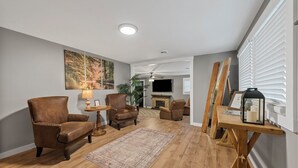 Ein Wohnzimmer mit Kamin, Ledersesseln, Teppich und Kunstwerken an der Wand.