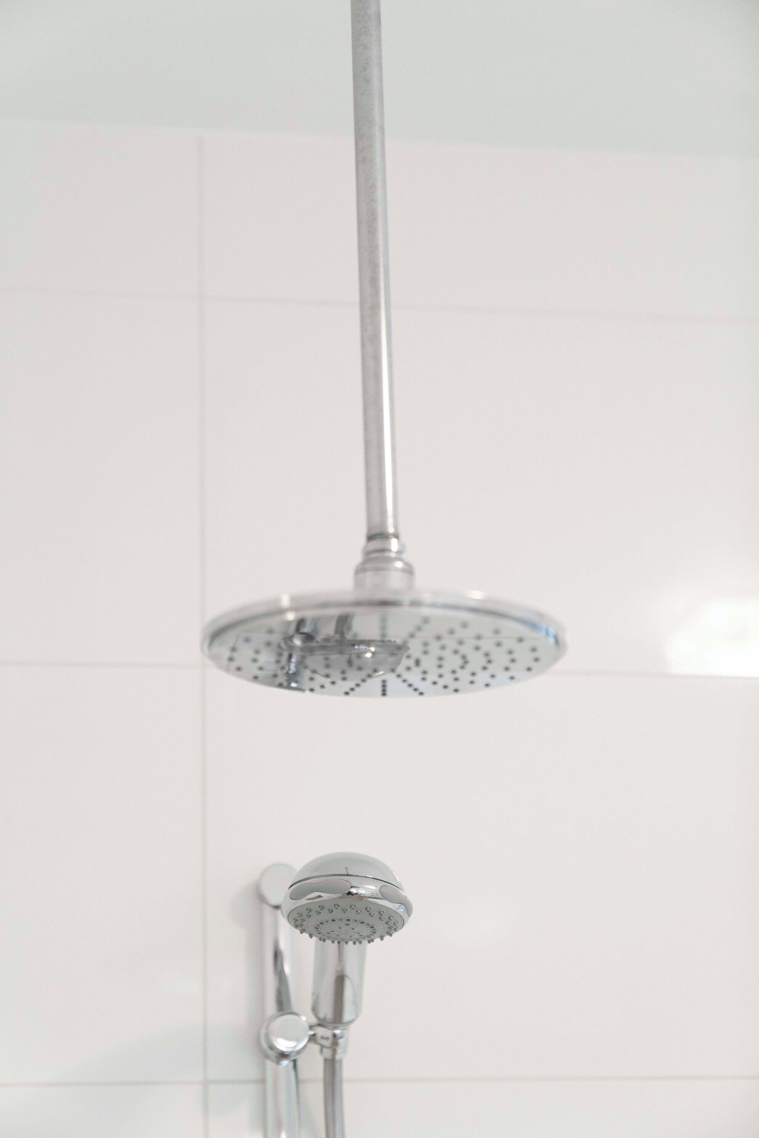A shower with a handheld showerhead and a fixed overhead showerhead.