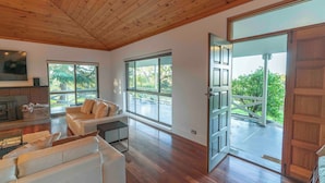 A spacious living area with a wooden ceiling, large windows, a fireplace, and a view of the outdoors. - The Hideaway by Gatt Wines (Flaxman Valley)