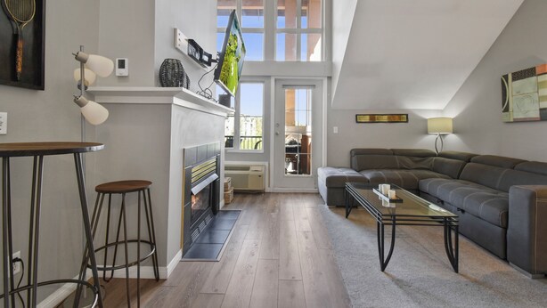 Un salon moderne avec une cheminée, un canapé, une table basse et un téléviseur fixé au mur.