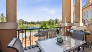 Un balcon avec une table, des chaises et un barbecue.