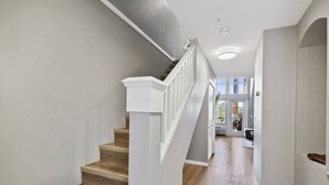 Un escalier avec des marches en bois et des rampes blanches menant à une pièce dotée d’une grande fenêtre.