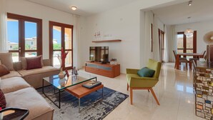 A modern living room with a sofa, coffee table, TV, and a dining area with chairs and a table. - Luxury Villa Retreat with Unmatched Elegance and Serenity (Paphos)