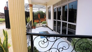 Un balcón con baranda de metal, plantas en macetas y vista a la calle.