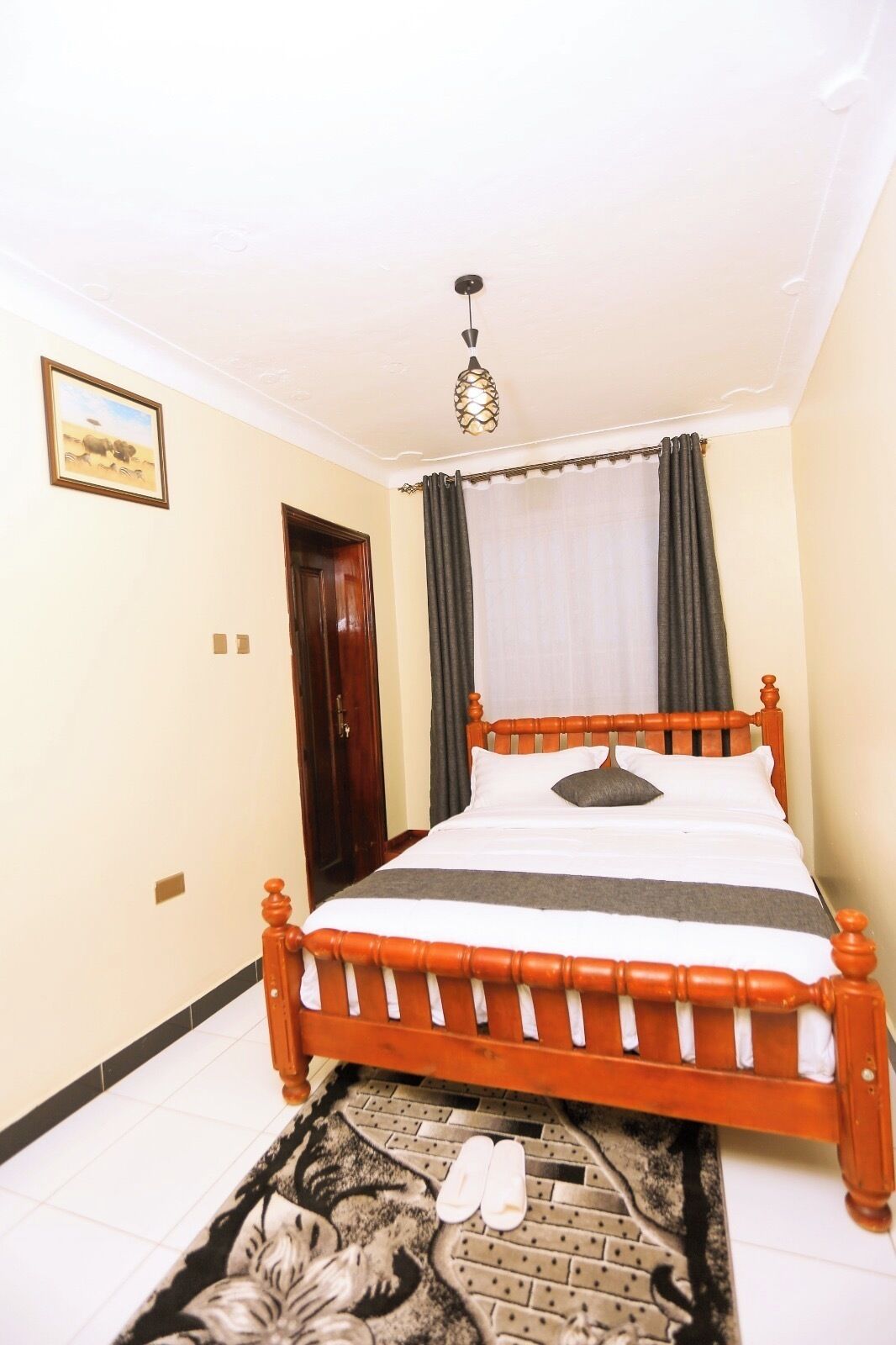 A bedroom with a wooden bed, a patterned rug, and a pair of shoes on the floor.