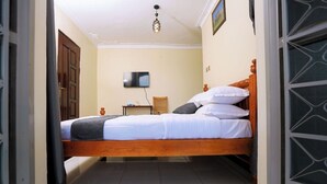 Un dormitorio con una cama de madera, una mesita de noche, una silla y un televisor en la pared.