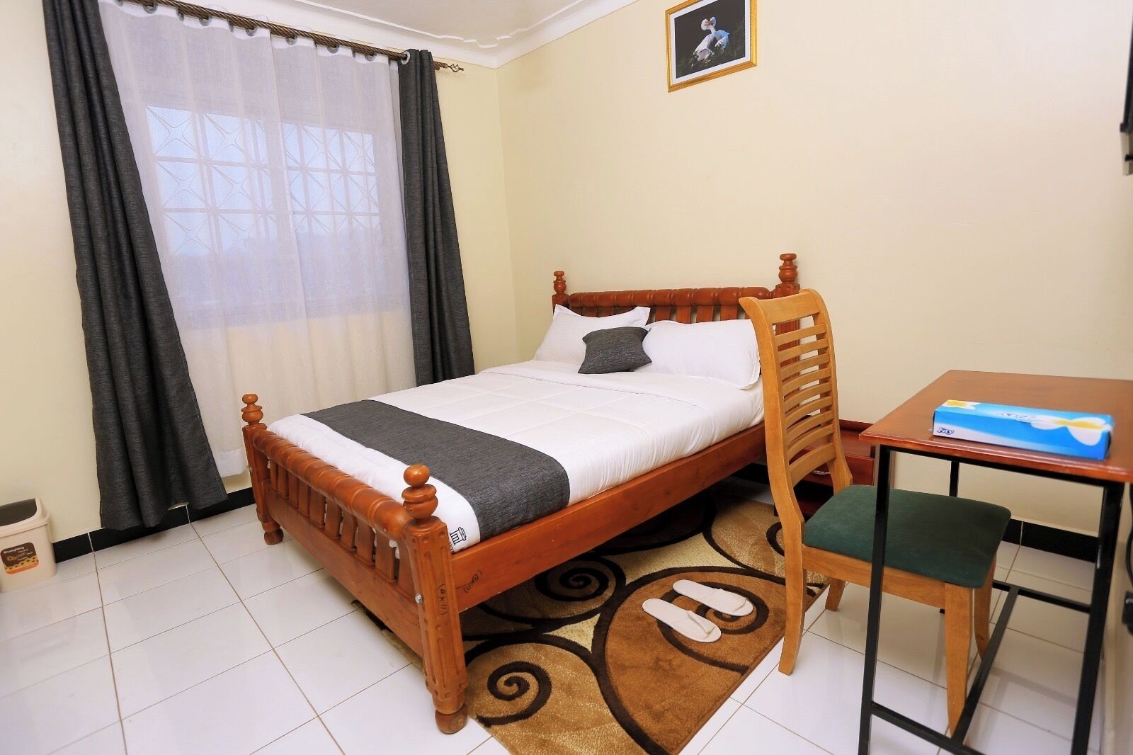 A neatly arranged bedroom with a wooden bed, a small table, and a chair.