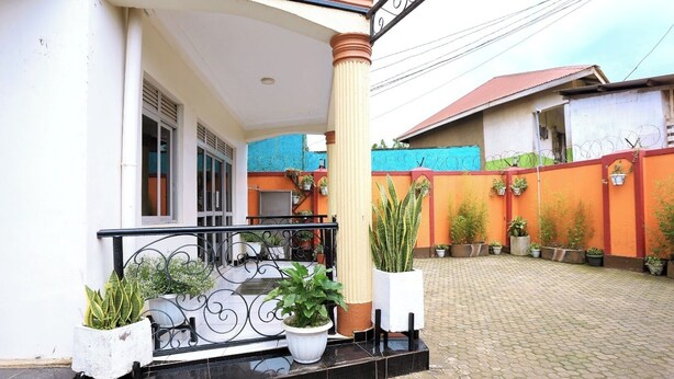 Un patio con suelo de baldosas, un edificio blanco con balcón y plantas en macetas.