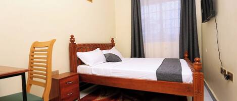 Un dormitorio ordenado con cama de madera, un escritorio y una silla.