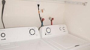 Une rangée de machines à laver blanches, dotées de panneaux de commande et de câbles d’alimentation.