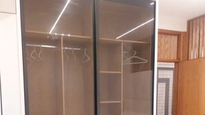 Ein begehbarer Kleiderschrank mit Schiebetüren, Holzböden und Kleiderstangen.