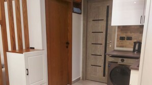 Eine kleine Küche mit Waschmaschine, Holzschränken und einer weißen Arbeitsplatte.