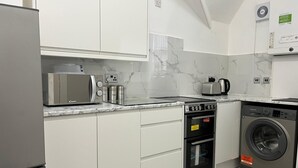 Eine moderne Küche mit weißen Schränken, einer eingebauten Mikrowelle, einem Gasherd, einem Backofen und einer Waschmaschine mit Frontlader.
