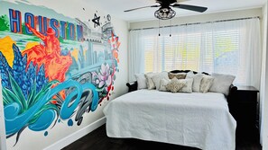 Experience the vibrant city of Houston in this unique bedroom featuring a bold mural and a comfortable white bed.
