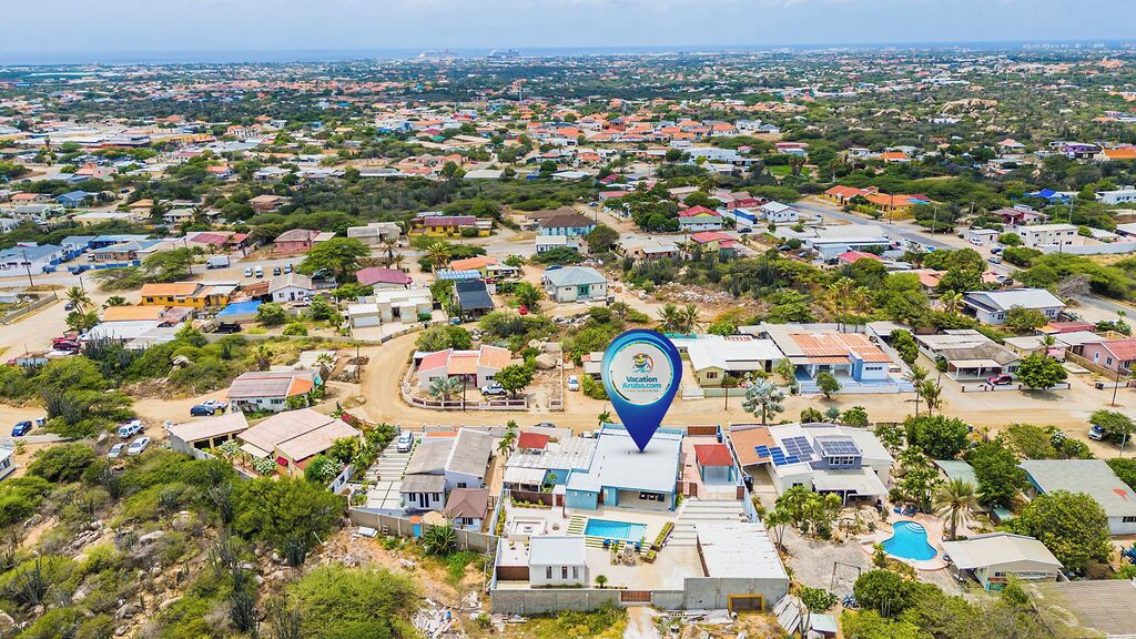 An aerial view of a residential area with houses, a swimming pool, and solar panels.
