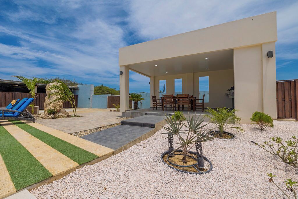 Ein moderner Außenbereich mit Terrassensitzgelegenheiten, einem Pool und einem angelegten Garten.