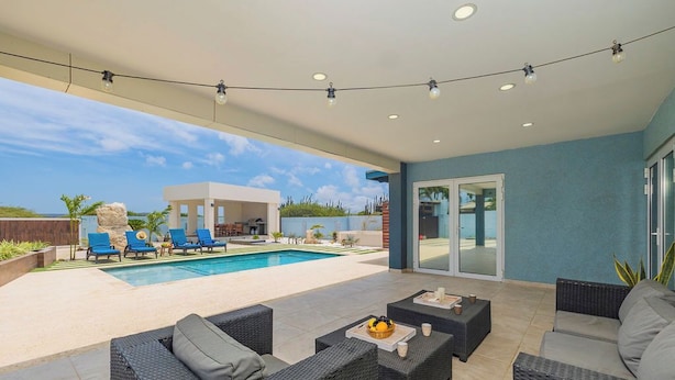 Un espace extérieur abrité comprenant une piscine, des chaises longues et du mobilier d’extérieur.