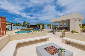 A pool area with a fire pit, lounge chairs, and a covered seating area.