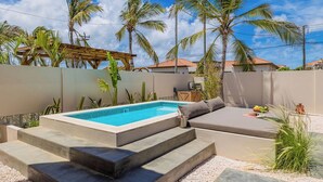 Ein Pool mit Stufen, umgeben von Palmen und einer überdachten Sitzgelegenheit.