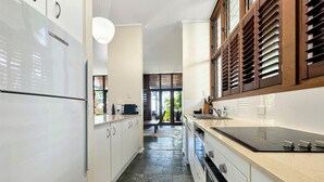 Een moderne keuken met witte kasten, een zwart fornuis en een stenen vloer.