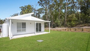 A single-story house with a covered patio, a fenced yard, and a grassy lawn.