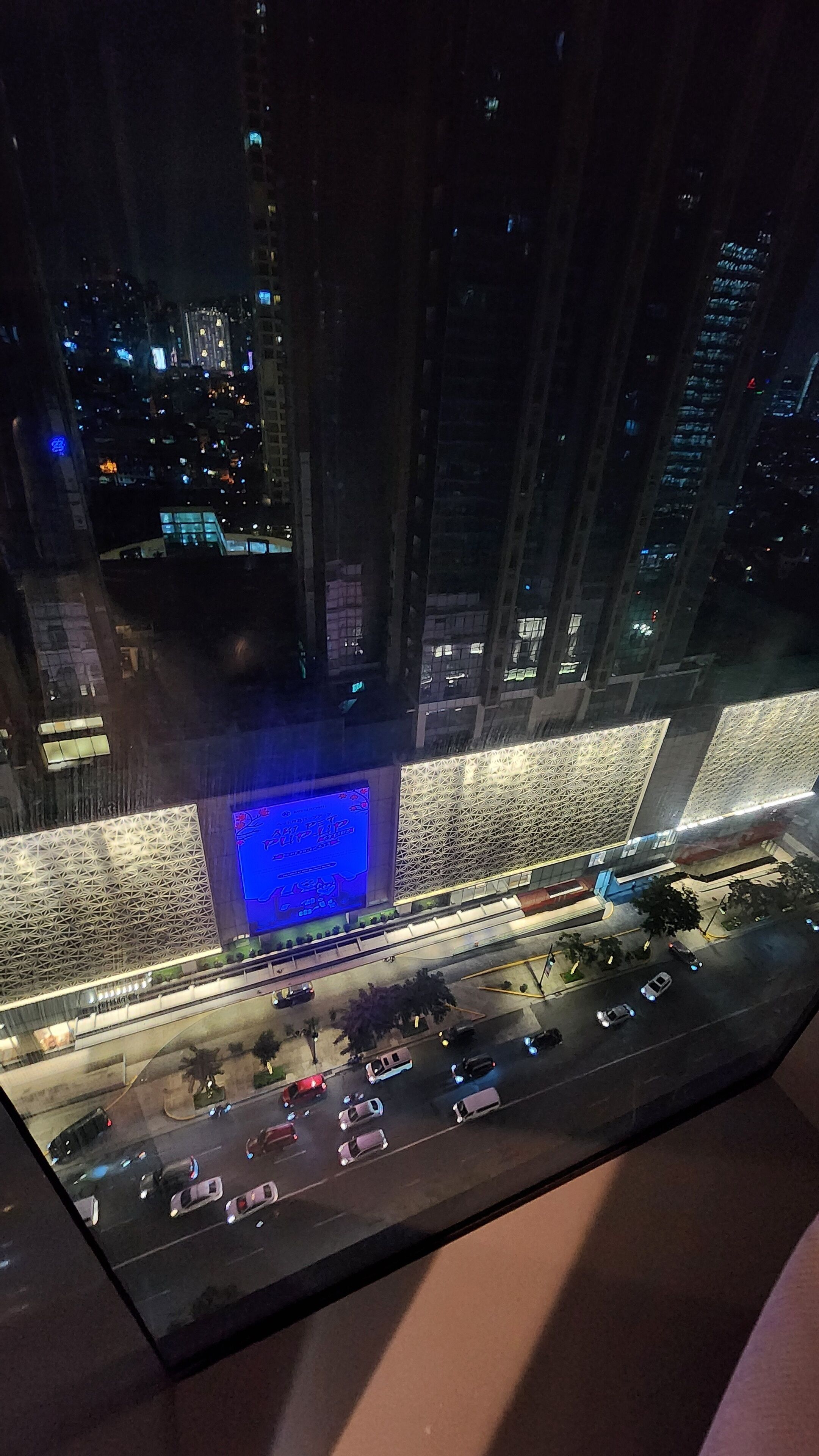 A nighttime cityscape with illuminated buildings and a busy street below.