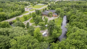An aerial view of a lodge surrounded by dense forest, with a river running through the property. - Riverside Retreat | Fishing | WiFi | Pet-Friendly (Aitkin)