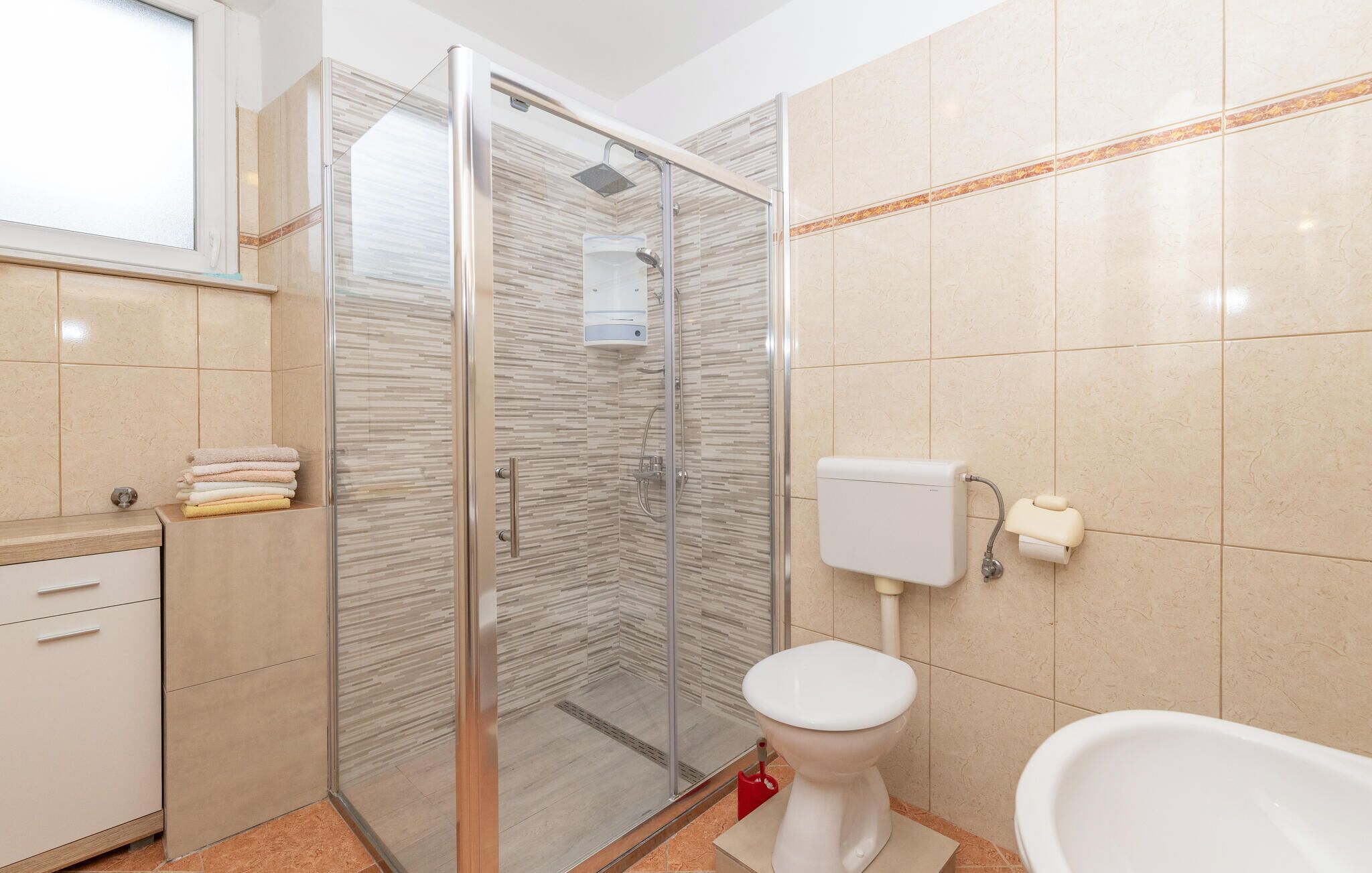 A modern bathroom with a glass shower enclosure, a toilet, and a sink with a cabinet.