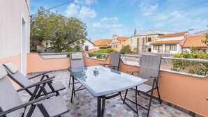 Un balcone con tavolo e sedie in vetro, affacciato su una zona residenziale con edifici tradizionali.