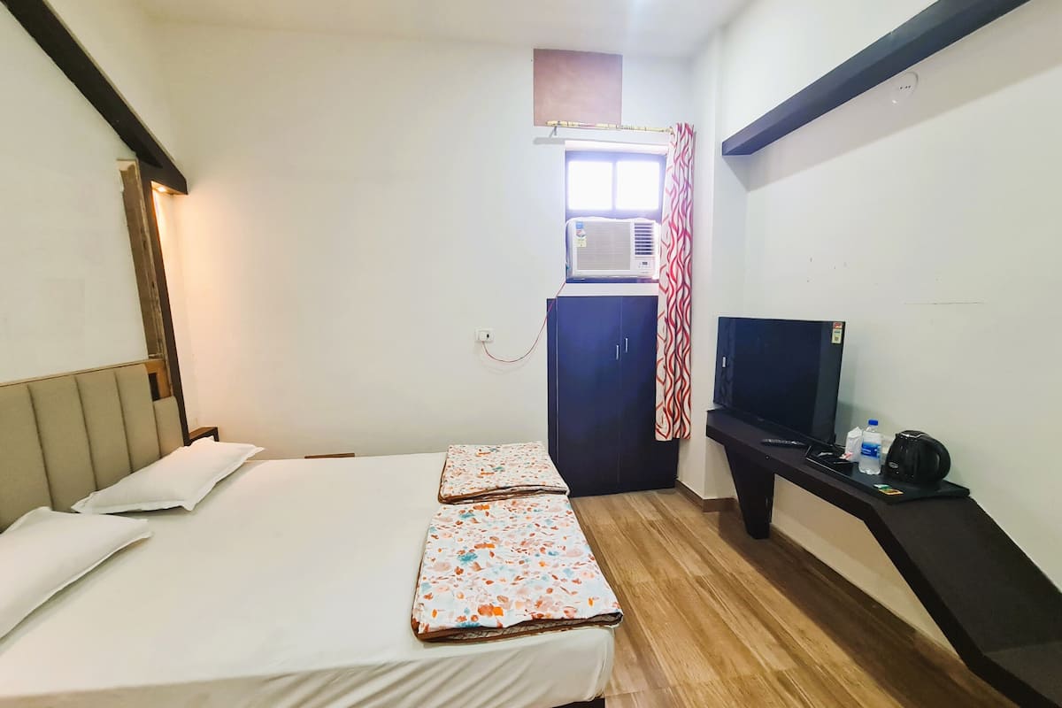 Una camera d'albergo con un letto, una TV, un armadio e un condizionatore d'aria.