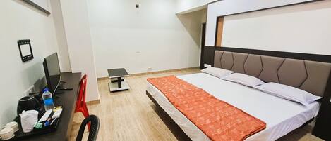 Una camera d'albergo con un letto, una scrivania con un computer, una sedia e un tavolino.