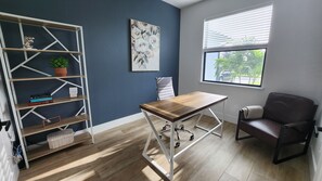 Work or unwind in a spacious area with a table and comfortable chair, featuring shelving for storage and display.