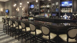 A bar area with a long counter, multiple chairs, and a television screen. - The Manhattan Club (New York)