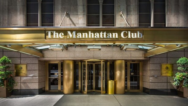 The Manhattan Club entrance with a classic design, featuring a prominent sign, a revolving door, and a stone facade. - The Manhattan Club (New York)