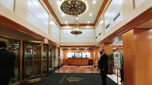 A hotel lobby with a marble reception desk, a large chandelier, and a revolving door. - The Manhattan Club (New York)