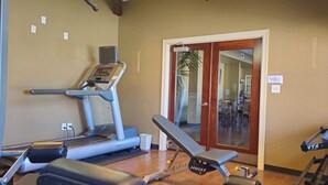 Una sala de gimnàstica amb cinta de córrer, banca de presses i altres aparells d'exercici.