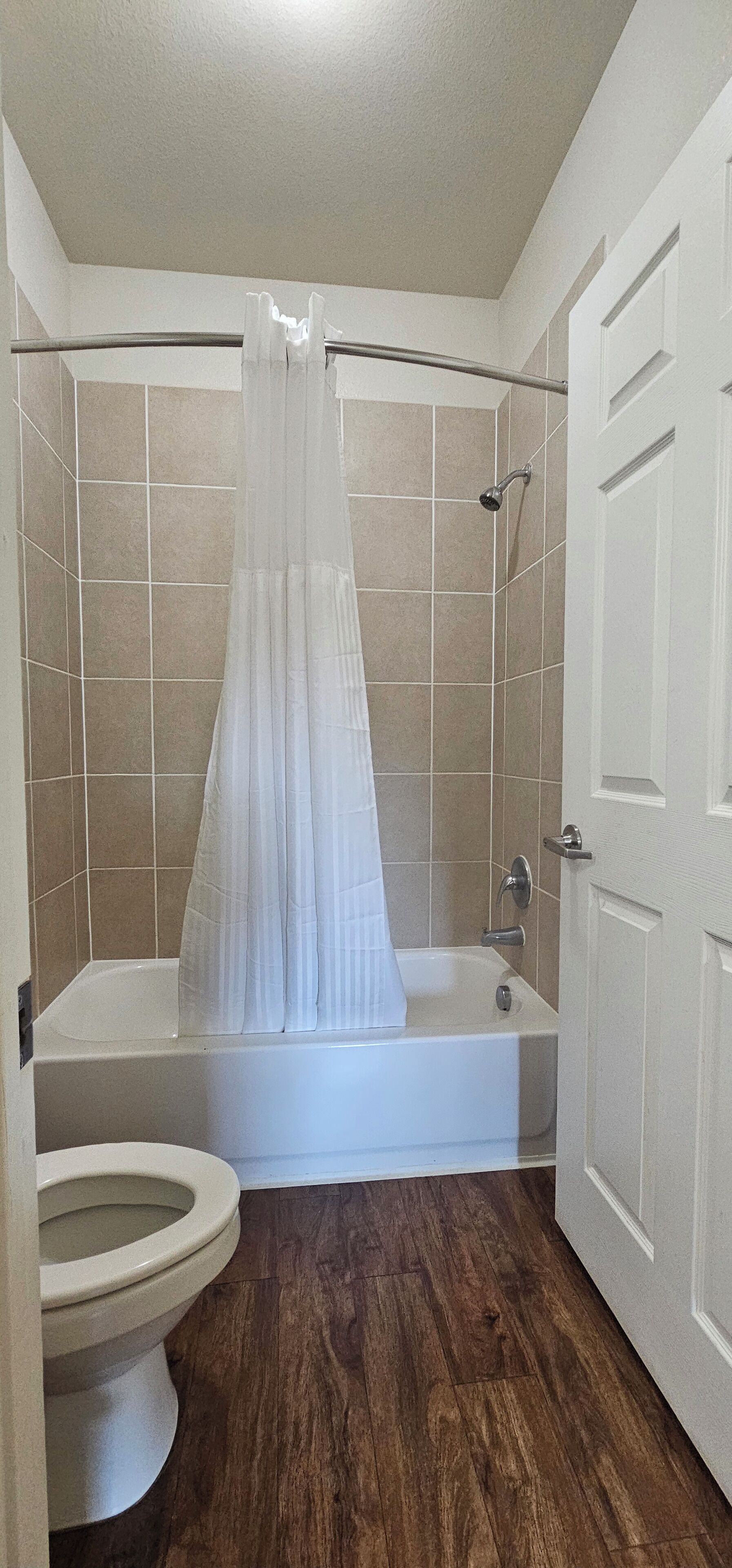 Een badkamer met bad, toilet en douchegordijn.