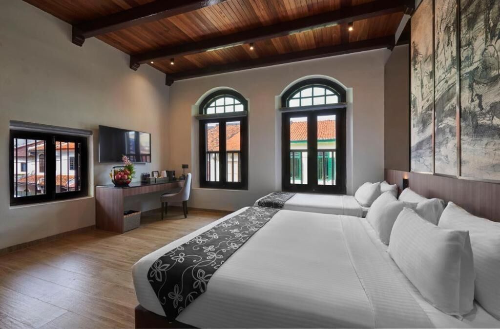 A hotel room with two beds, a desk, and a TV.