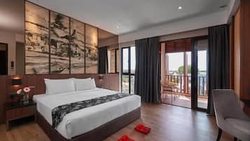 A modern hotel room with a large bed, a view of the city, and a balcony with outdoor furniture.